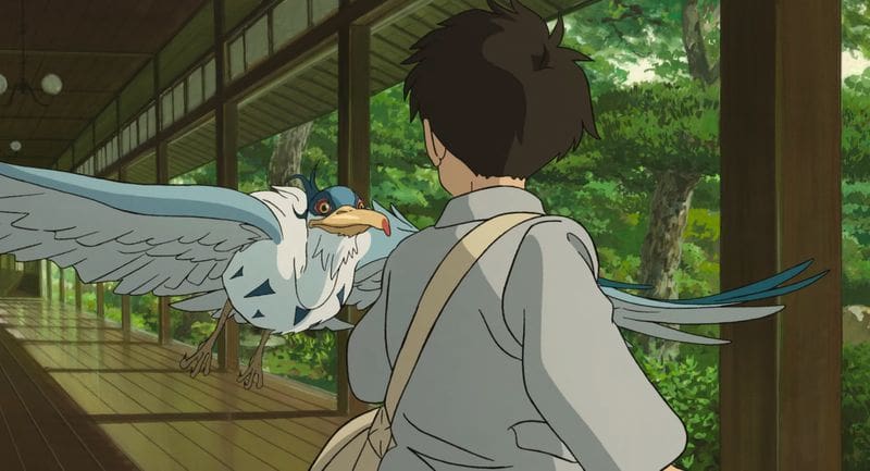 A grey heron is flying toward a young boy and main character, Mahito in a Japanese home. Image is from Hayao Miyazaki's "The Boy and the Heron", a Studio Ghibli film.