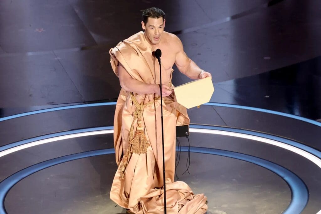 John Cena at the 96th Academy Awards ceremony, covered in a curtain-like material, presenting the award for Best Costume Design.