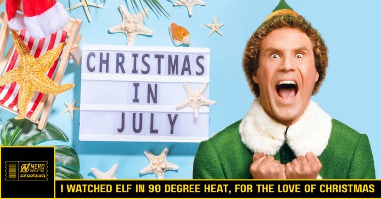 Elf in a green suit with a white fur collar, shouting happily beside a lightbox reading 'CHRISTMAS IN JULY' against a blue background.