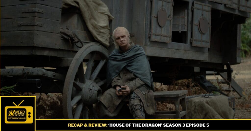 Older man in a cloak sits beside a large wagon wheel in a dusty outdoor scene; a crow rests nearby.
