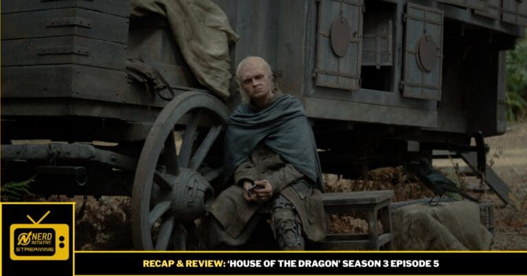 Older man in a cloak sits beside a large wagon wheel in a dusty outdoor scene; a crow rests nearby.