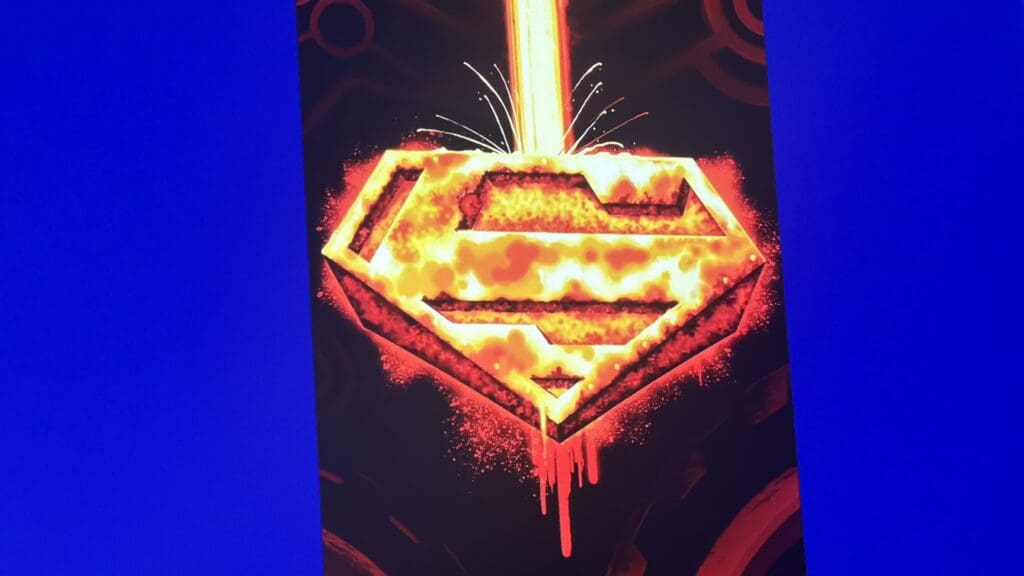 Fiery Superman S-shield logo glowing in orange and yellow on a dark background with blue side panels